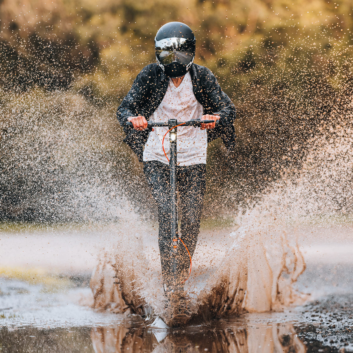 Rider on INMOTION Climber scooter splashing through muddy water, showcasing durability.