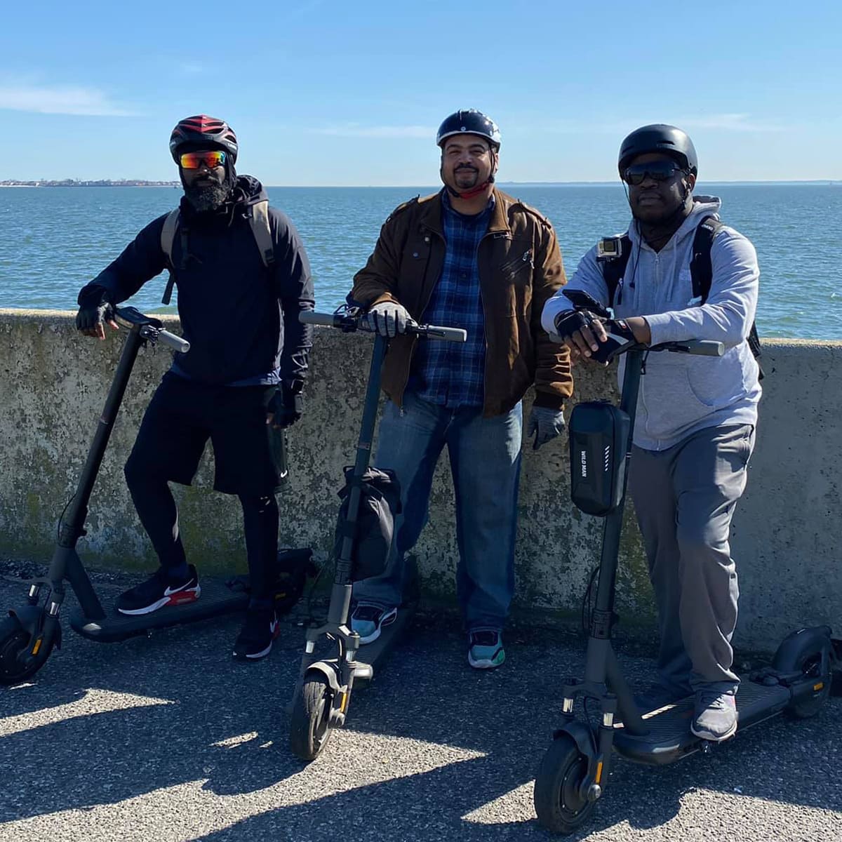 Group of three men with INMOTION S1F scooters by the water