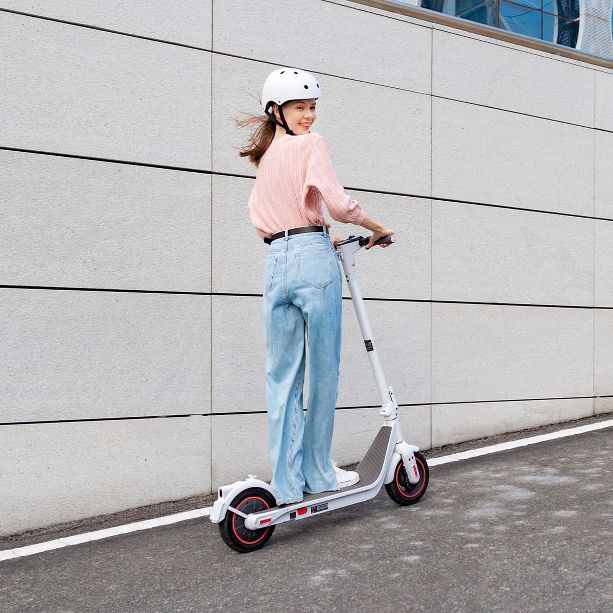 Woman riding INMOTION Air Pro electric scooter on urban street