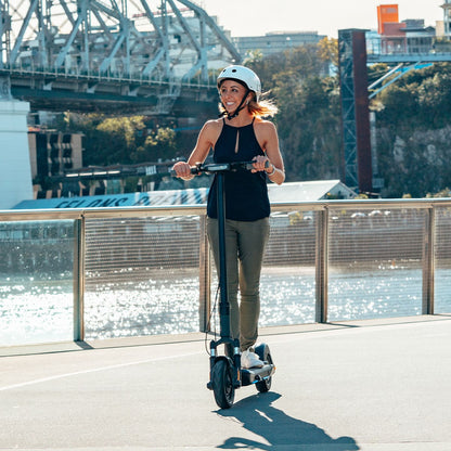 Woman riding INMOTION S1F electric scooter by the water in sunny weather