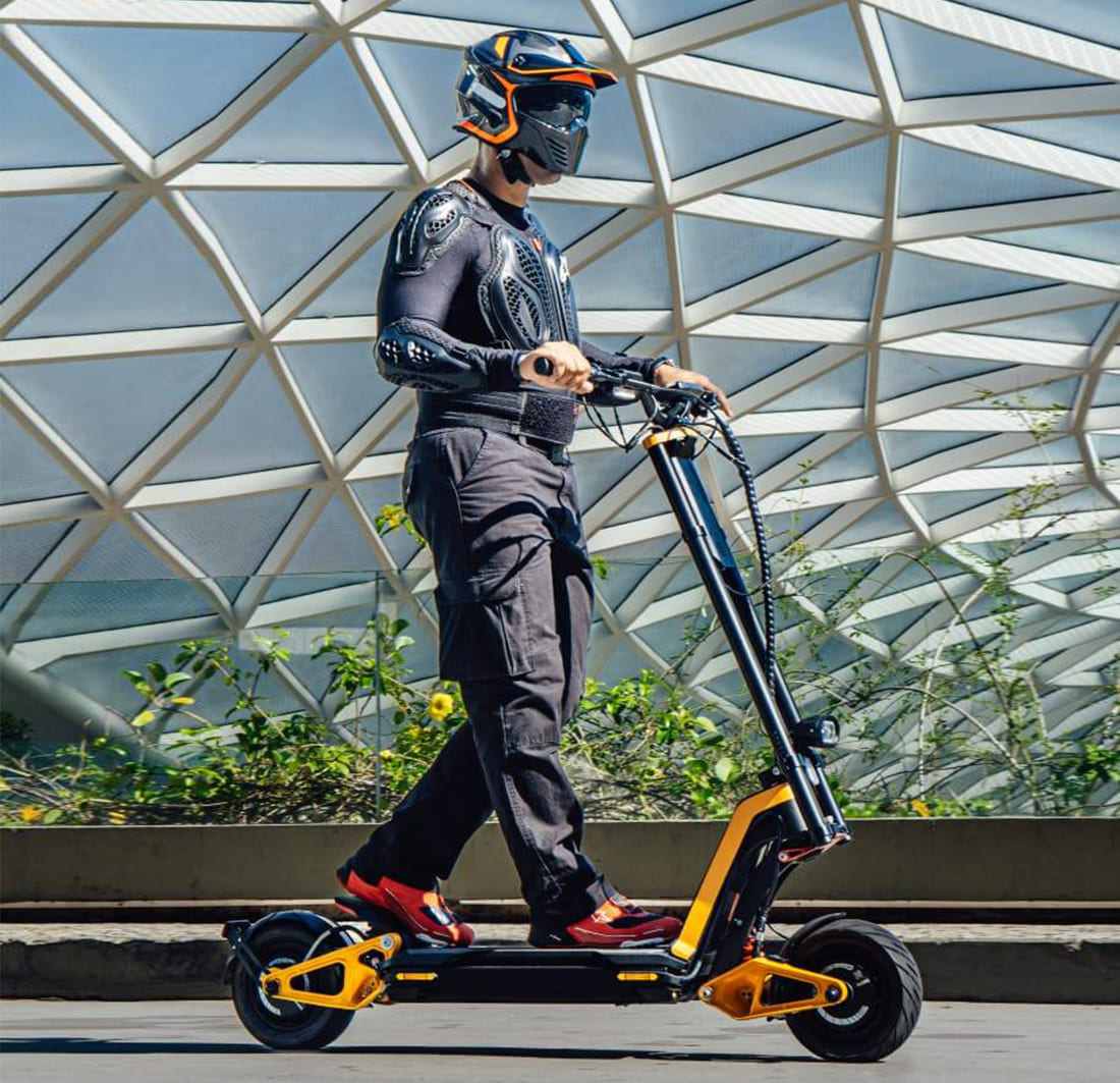 Rider in protective gear on INMOTION RS electric scooter against modern architecture