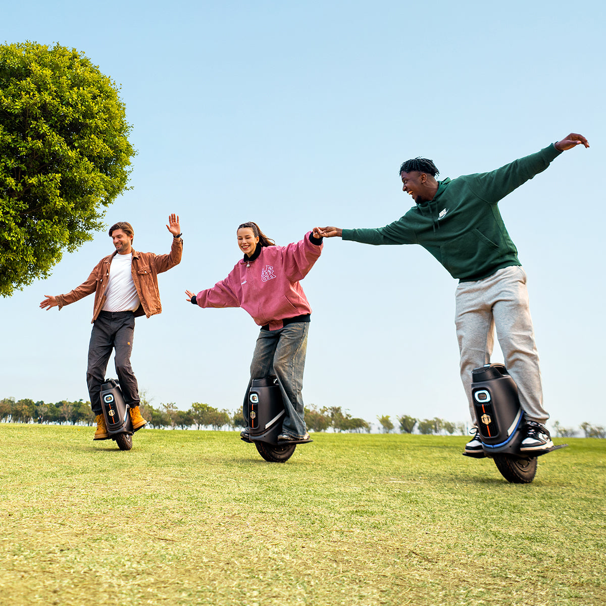 Three friends enjoying INMOTION V9 electric unicycles in a park.