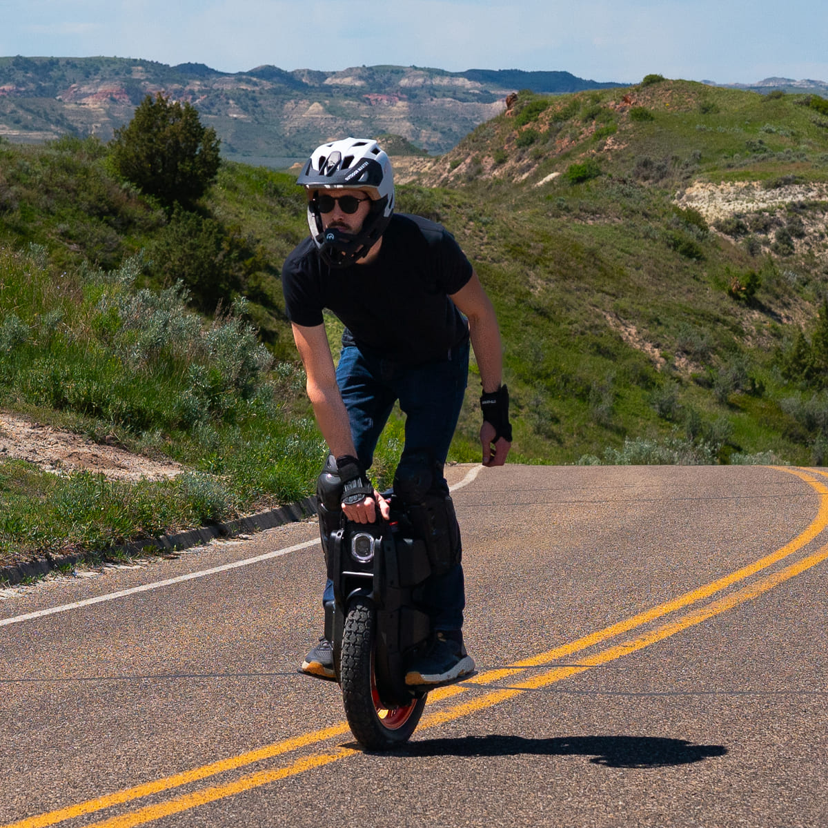 Rider showcasing INMOTION V13 Pro electric unicycle on scenic road.