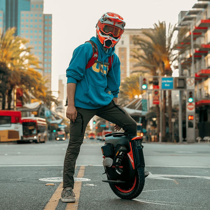 Rider with helmet showcasing INMOTION V12 Pro unicycle in urban setting.