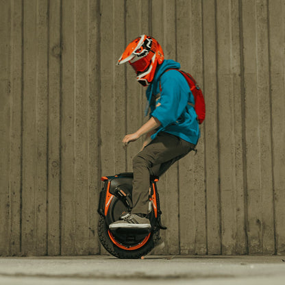 Rider performing tricks on INMOTION V12 Pro unicycle in urban environment.