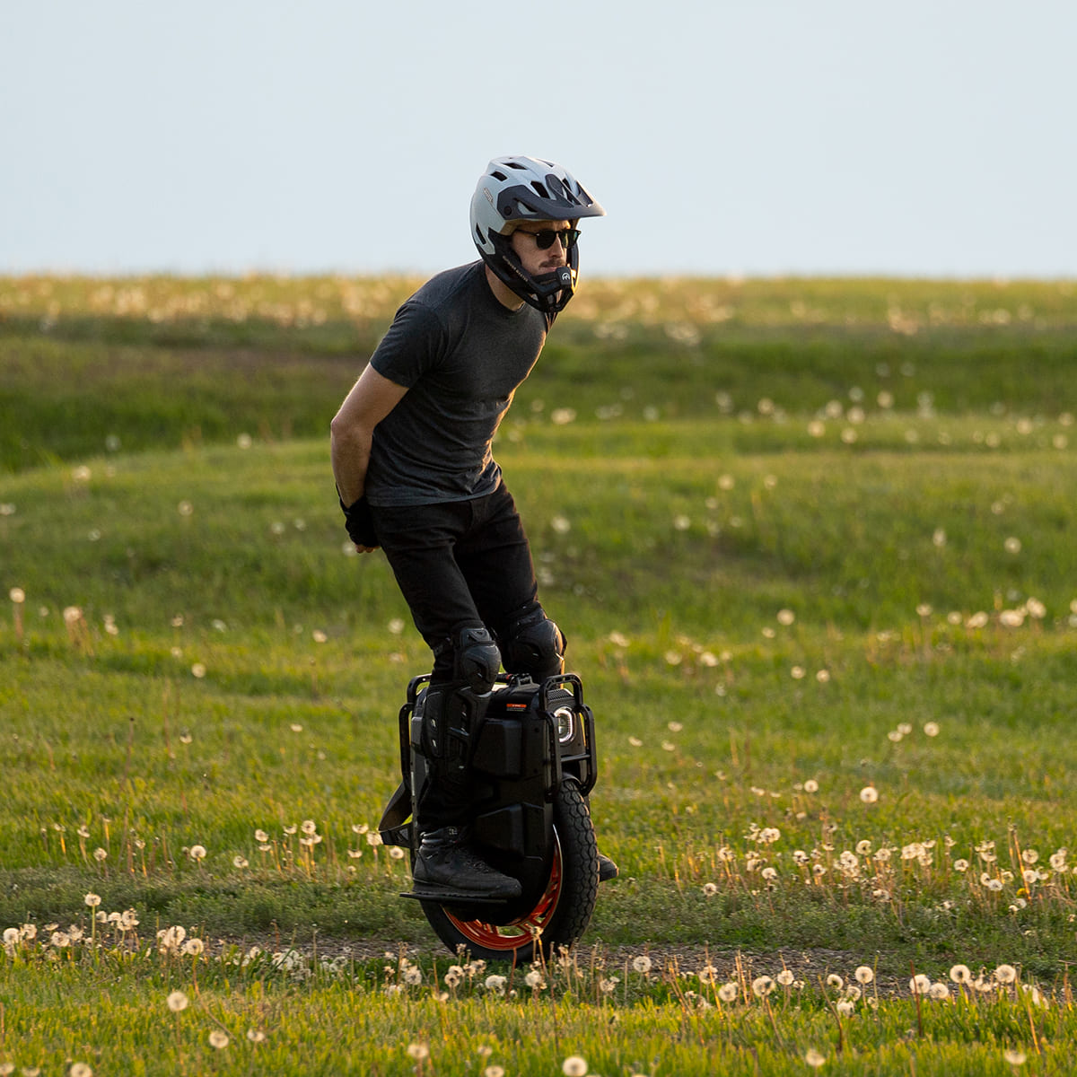 Rider demonstrating balance on INMOTION V13 Pro unicycle on grassy field.